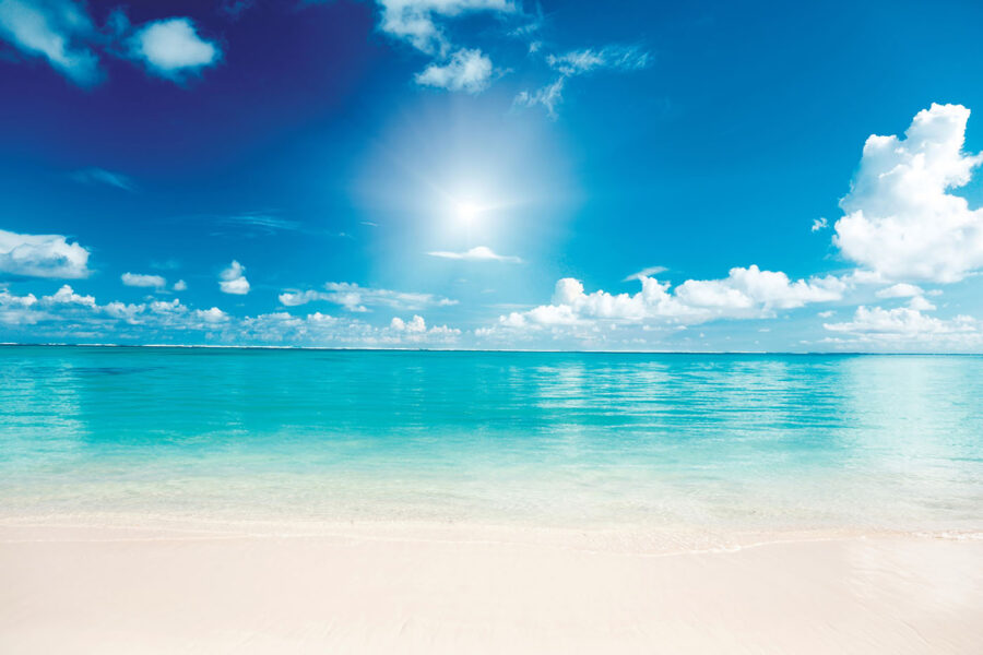 Blauwe lucht met wolken en een zandstrand
