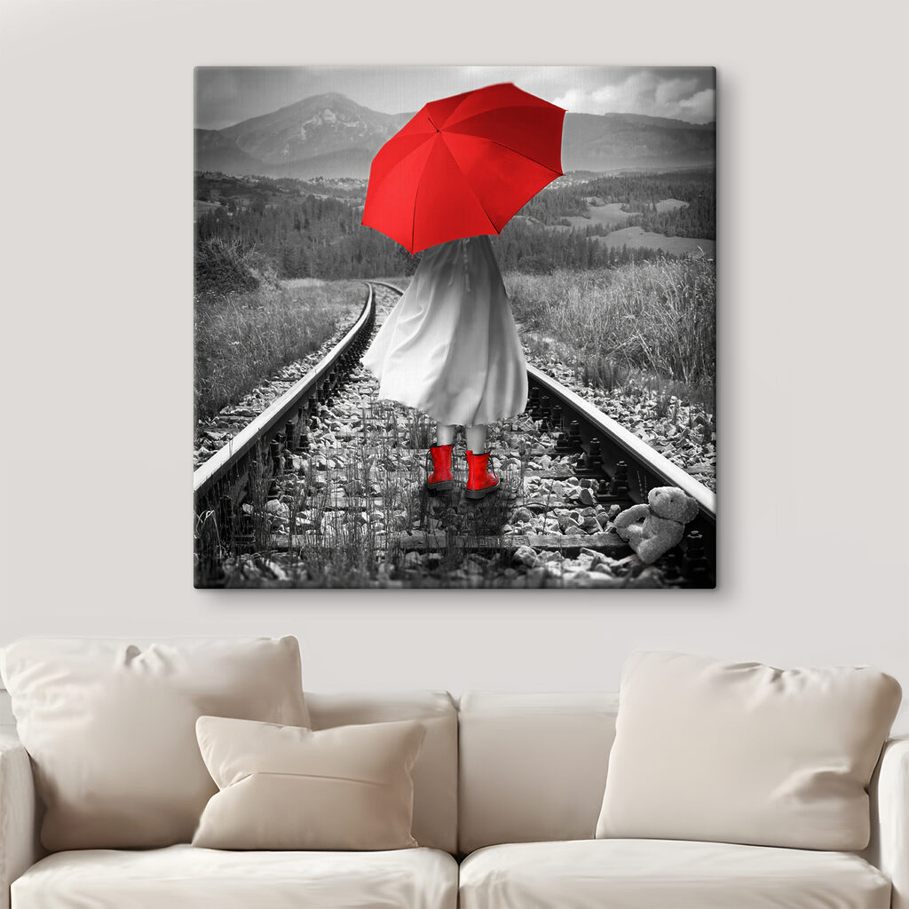 A person with a red umbrella on a train track