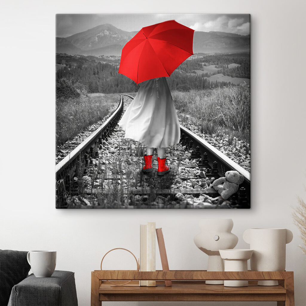 A person with a red umbrella on a train track