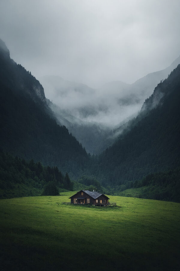 Huis in een veld met bergen op de achtergrond Huis in een veld met bergen op de achtergrond